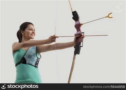 Young woman practicing archery isolated over gray background