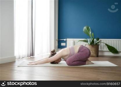 Young woman practicing yoga at home indoor, copy space. Girl relax meditation in child’s pose, full length. Relaxing and doing yoga, resting, stretching. Wellness and healthy lifestyle. Balasana beauty. Young woman practicing yoga at home indoor, copy space. Girl relax meditation in child’s pose, full length. Relaxing and doing yoga, resting, stretching. Wellness and healthy lifestyle. Balasana
