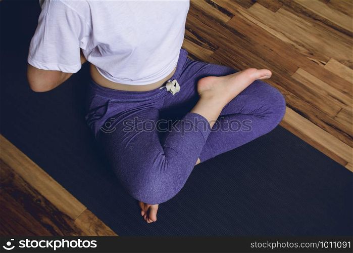 Young woman practicing yoga in home. Girl doing pose on a mat. Healthy lifestyle and fitness concept