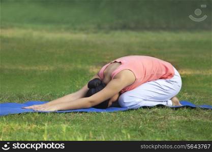 Young woman practicing yoga in lawn
