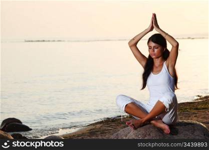 Young woman practicing yoga near the ocean