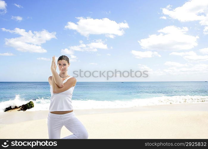 Young woman practicing yoga on the beach