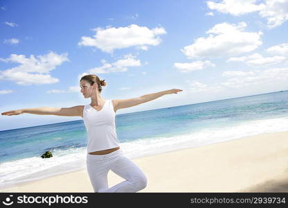 Young woman practicing yoga on the beach