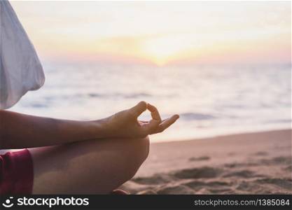 Young woman practicing yoga on the tropical beach at sunset