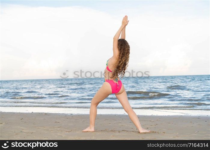 Young woman practicing yoga pose on the beach in summer. Healthy lifestyle and meditation.. Young woman practices yoga on the beach in summer.
