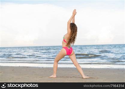 Young woman practicing yoga pose on the beach in summer. Healthy lifestyle and meditation.. Young woman practices yoga on the beach in summer.