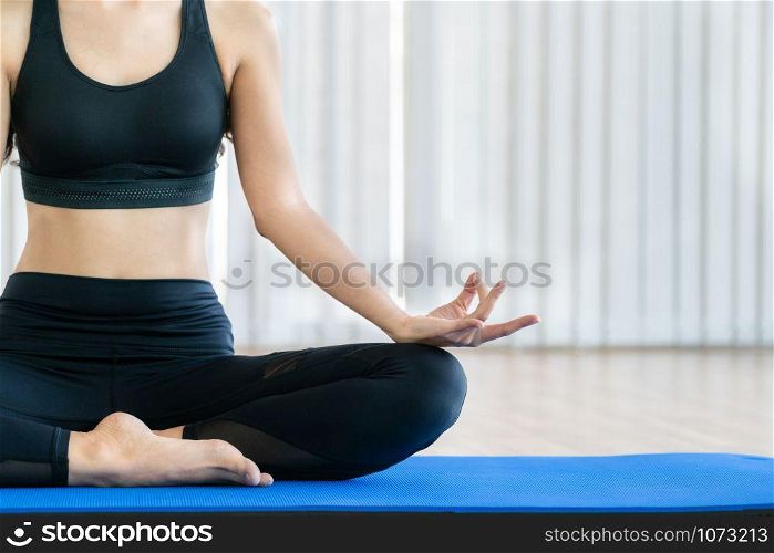 Young woman practicing yoga position in an indoor gym studio. Healthy and wellness lifestyle concept.
