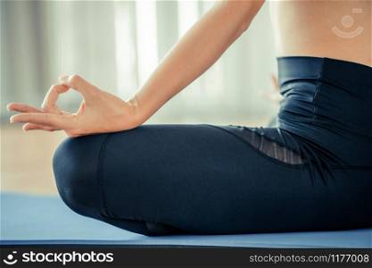 Young woman practicing yoga position in an indoor gym studio. Healthy and wellness lifestyle concept.