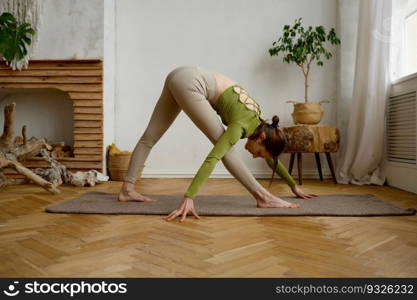 Young woman practicing yoga standing in head down asana pose. Stretching workout exercise at home. Young woman practicing yoga standing in head down asana pose