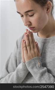 young woman praying home with eyes closed