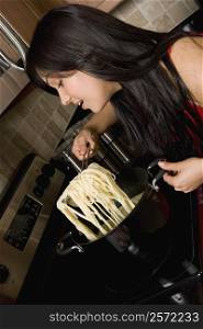 Young woman preparing noodles in the kitchen