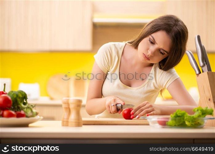 Young woman preparing salad at home in kitchen