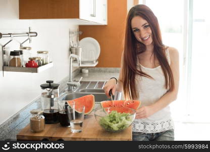 Young woman preparing watermelon in the kitchen