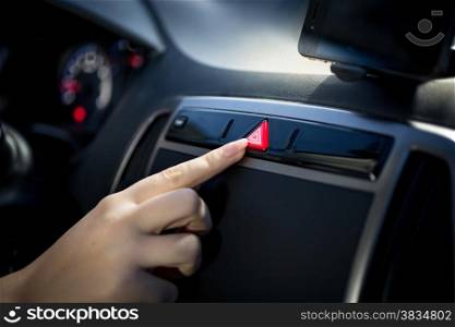 Young woman pressing emergency button on car dashboard