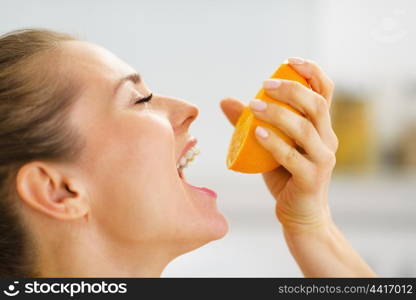 Young woman pressing orange juice in mouth