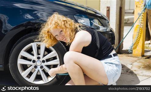 young woman pumping up tire car petrol station sunny summer day