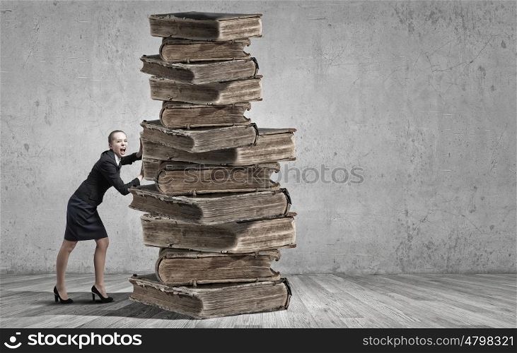 Young woman pushing huge pile of old books. Books and reading