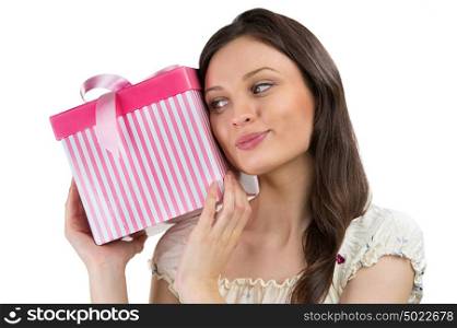 Young woman puts her ear to the present wrapped in red paper, isolated on white