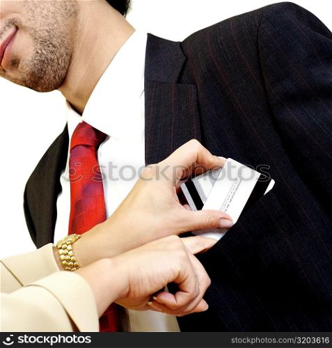 Young woman putting credit cards into young man&acute;s pocket