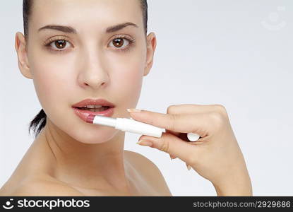 Young woman putting lipstick on her lips