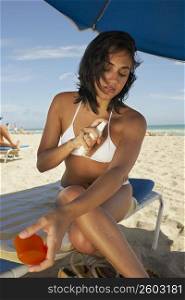 Young woman putting on sun tan lotion