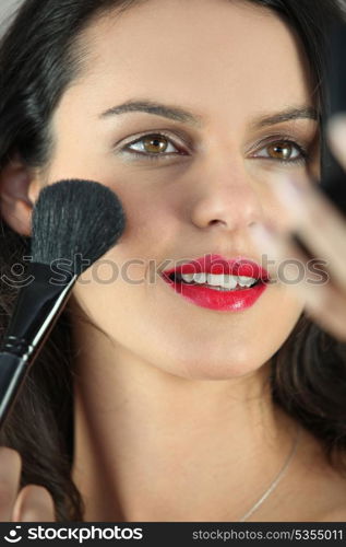 Young woman putting some make-up on