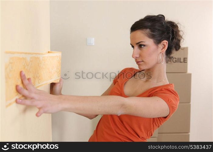 Young woman putting up wallpaper