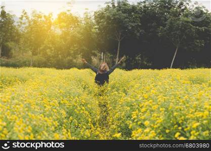 young woman raise her hand up in yellow Chrysanthemum flower field, feeling happy and free