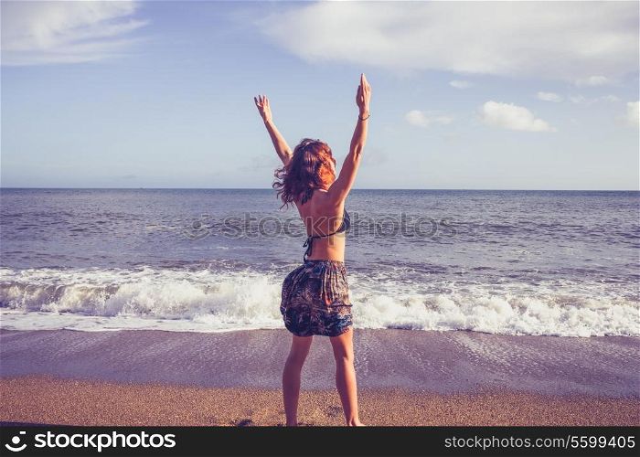 Young woman raising arms on beach