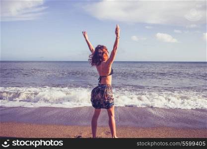 Young woman raising arms on beach