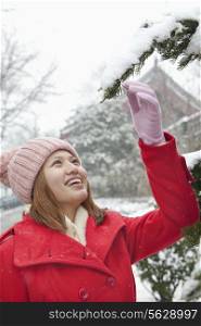 Young woman reaching for a branch in the snow