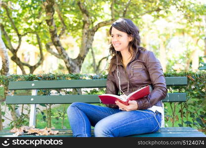 Young woman reading a book and relaxing at the park