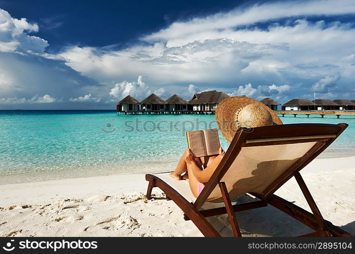 Young woman reading a book at the beach