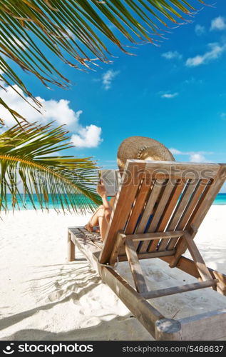 Young woman reading a book at the beach