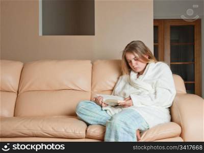 young woman reading a book on sofa