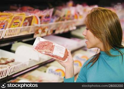 Young woman reading a price tag on a packet in a supermarket