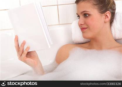 Young woman reading book in the bathtub