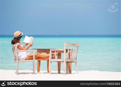 Young woman reading book on the beach and enjoy summer vacation. Young woman reading book during tropical white beach