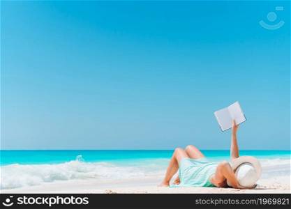 Young woman reading book on the beach. Young woman reading book during tropical white beach