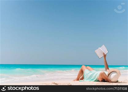 Young woman reading book on vacation during relaxing on the sandy beach. Young woman reading book on chaise-lounge on the beach