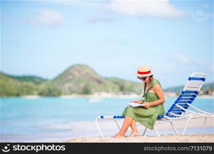 Young woman reading book on vacation. Young woman reading book on chaise-lounge on the beach