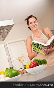 Young woman reading cookbook in the kitchen, looking for recipe