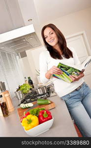 Young woman reading cookbook in the kitchen, looking for recipe