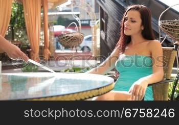 young woman reading good news in a letter sitting in a cafe
