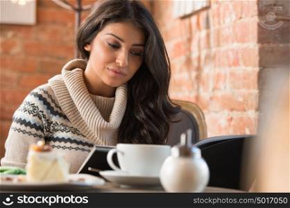 Young woman reading menu in a cafe indoors. Shallow depth of field.