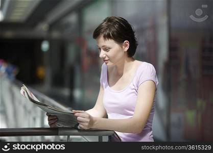 Young woman reading newspaper in shopping centre Voronezh