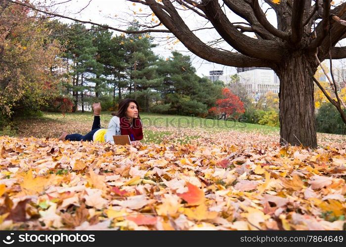 Young woman reading outdoors amoung the colorful autumn leaves