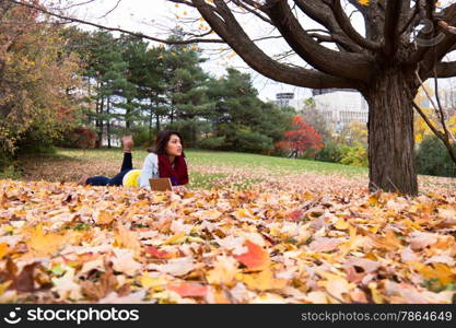 Young woman reading outdoors amoung the colorful autumn leaves