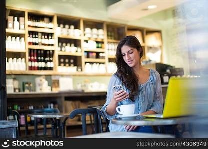 Young woman reading smartphone texts in cafe