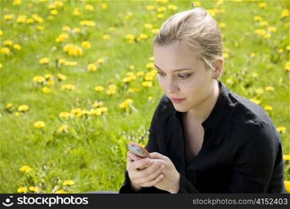 Young Woman Reading SMS In The Meadow